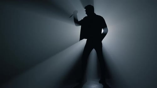 Silhouette Man Holding Knife in Hand in Darkness