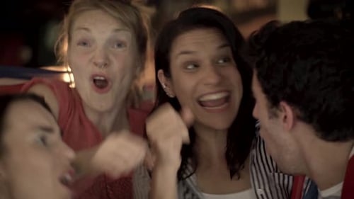 Football fans cheering while watching televised match at sports bar together