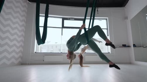 Graceful Women Practicing Aerial Yoga in Modern Studio