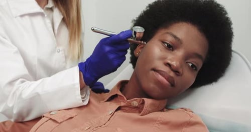 Woman Beautician Performs Dermabrasion Cosmetic Procedure on Clients Face