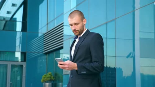 Young Businessman Using Smart Phone Near Office and Celebrating Achievement. Business Man Read Good