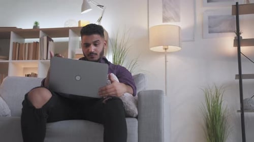 Young Adult Works on Laptop Computer at Home