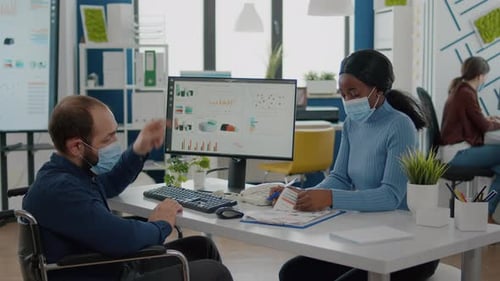 Un homme invalide et un employé africain portant des masques de protection travaillent ensemble