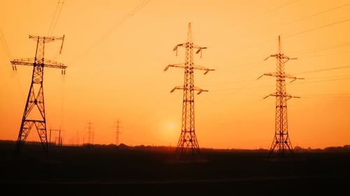 Electricity Pylons Silhouetted Against Vibrant Sunset Sky