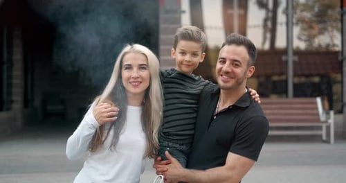 Portrait of a Smiling Happy Family Outdoor. Parents with a Child Are Looking at the Camera.