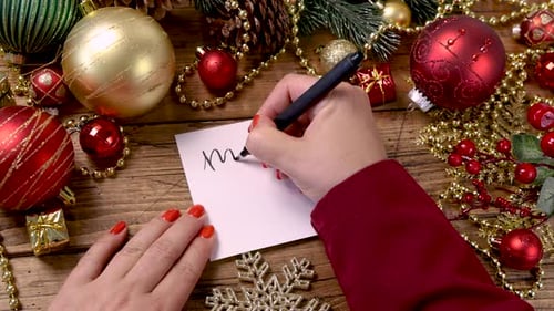 Writing a Christmas Card Surrounded by Decorations