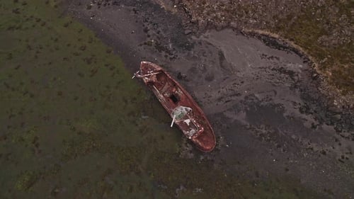 Drohne kreist bei Ebbe über altem Schiffswrack an der isländischen Küste
