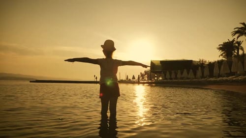 Silhouette of Happy Child Playing at the Beach at Sunset, Dreaming About Flying. Summer Vacation