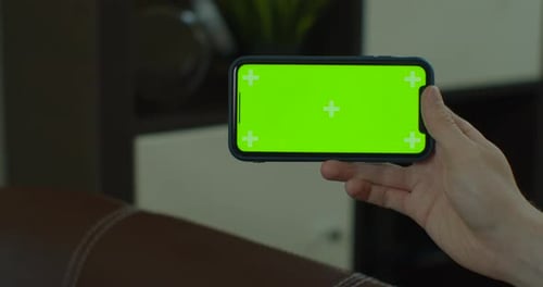 Close Up of a Man Hand Holding a Mobile Telephone with a Vertical Green Screen in Chroma Key