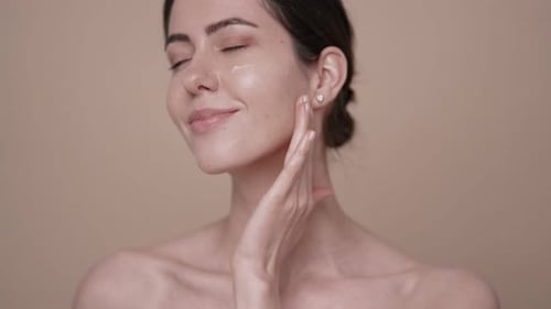 Young Woman Applying Cream on Her Face