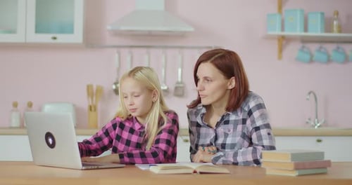 Young 30s Mother Watching for Her School Daughter Using Laptop for Digital Education. Online
