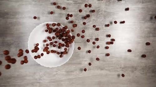 Chocolate Puffs Falling into White Bowl, Top View