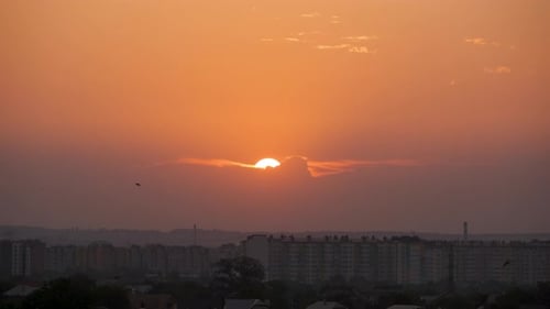 Evening Landscape with Bright Setting Sun Over Distant City High Rise Buildings at Sunset
