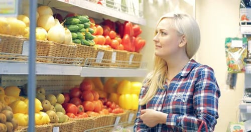 Young Smiling Woman Looking at Vegetables in the Store