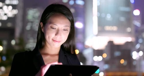 Woman Uses Tablet at Night in Urban Setting