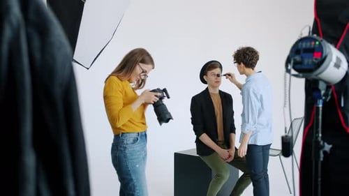 Cámara lenta de un maquillador que trabaja con un modelo masculino en un estudio fotográfico