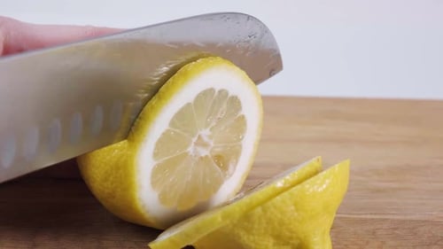 Slicing a Bright Yellow Lemon on Cutting Board