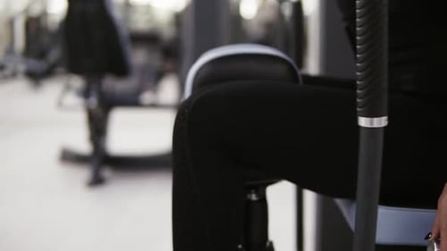Fisiculturista feminina realizando exercícios de adução por LED na academia