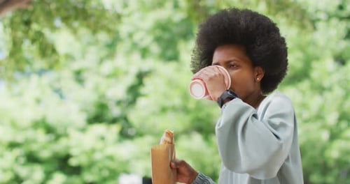 African american businesswoman eating and drinking takeaway coffee