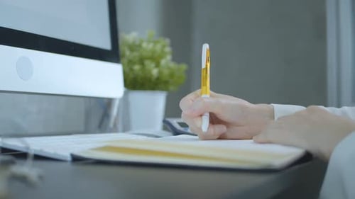 Person writing in notebook at office desk