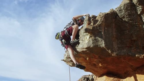 Mountaineer climbing on the hill with the help of rope