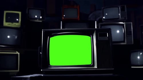 Retro TV Set with Green Chroma Key Screen in the Middle of Many Old TVs. Dark Tone. Dolly Out.
