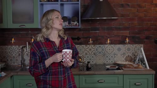 Woman Drinking from Mug in Kitchen