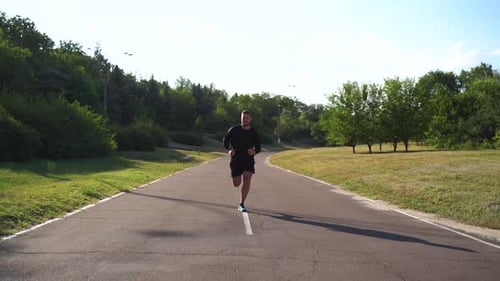 Man Jogging on Paved Path in Park