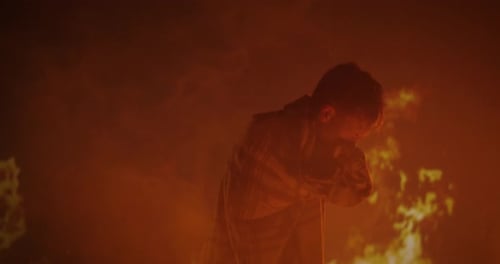 Young Adult Wrapped in Blanket Stands in Front of Flames