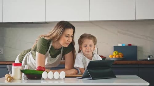 Woman and Child Baking in Kitchen with Tablet