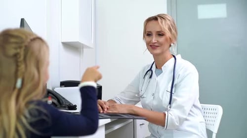 Woman Doctor Pediatrician Talking To Kid Girl Patient at Medical Checkup