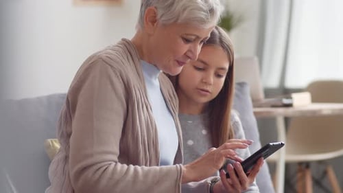 Grandmother and Grandchild Use Technology Together Indoors