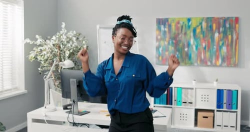 Elegant Feisty Girl Dressed in Blue Shirt and Stylish Glasses Dancing in the Middle of the Office