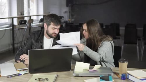 Geschäftsfrau streitet mit ihrem männlichen Kollegen im Büro, schließt sein Notizbuch und wirft Papiere