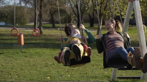 Family playing together at swing in public playground, Zagreb, Croatia.