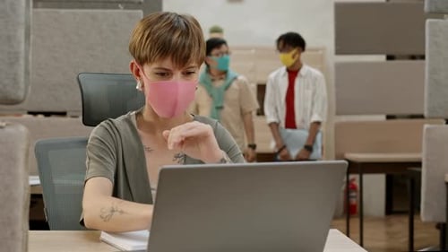 Female Office Worker Wearing Mask Working on Laptop