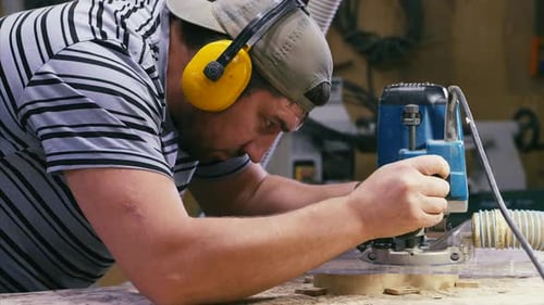 Man Using a Router in a Workshop