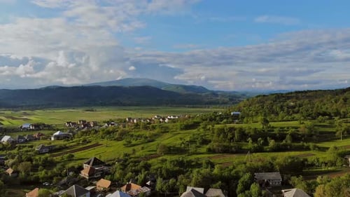 Sunny Summer Day and Small Village in Montain in a Blue Sky
