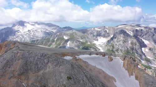 Aerial Shot of a Mountain Ridge Against Rocky Cliffs, Glacier and Snowy Peaks. Amazing Aerial View