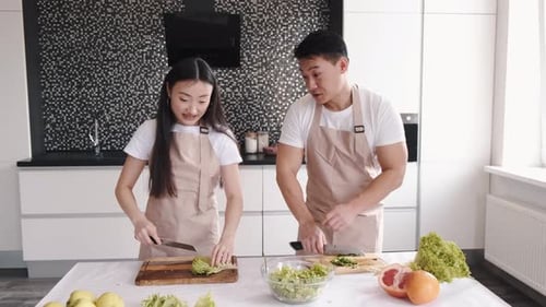 Smiling Couple Chops Vegetables in Modern Kitchen