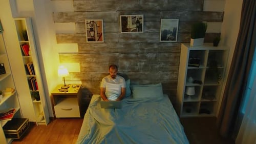 Aerial view of man using laptop in bed