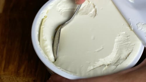 The woman opens a plastic jar with white cheese, cottage cheese, yogurt. Healthy dairy food.
