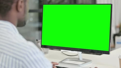 Rear View of African Man Using Desktop with Green Chroma Key Screen