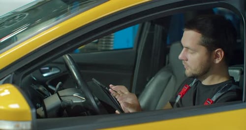 Mechanic Sitting in Car Doing Diagnostics on Digital Tablet
