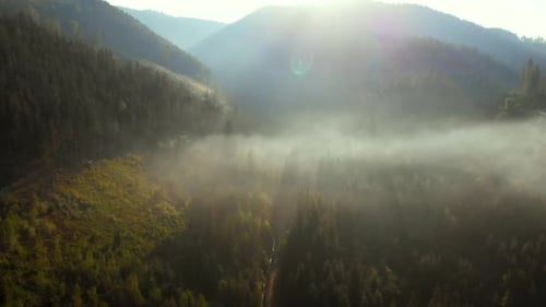 Aerial view of sunrise over foggy village in mountains.