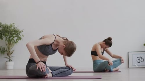 Women Practicing Yoga Stretch in Bright Studio