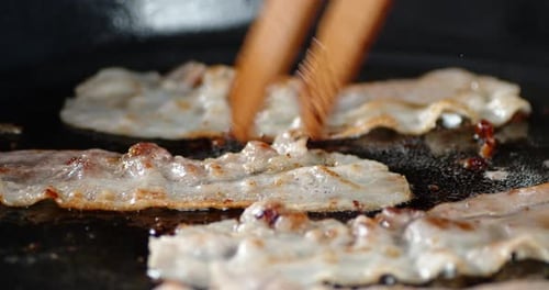 Bacon Is Fried for English Breakfast with Hot Steam. On a Black Background.