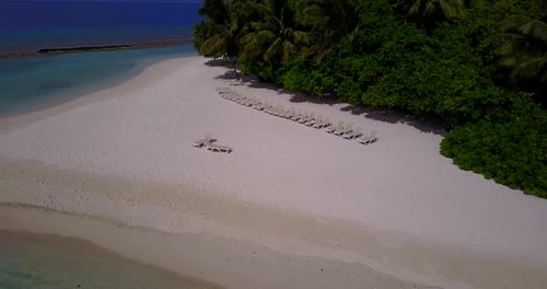 Daytime aerial tourism shot of a sandy white paradise beach and blue water background in hi res 4K