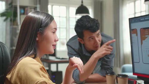 Asian Female Ux Architect Has Discussion With Male Design Engineer, They Work On Mobile Application