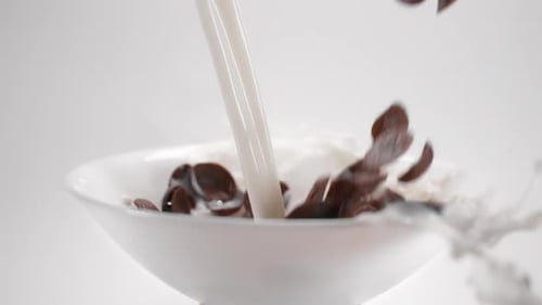 Milk and Chocolate Cereal Flakes Falling Into Bowl